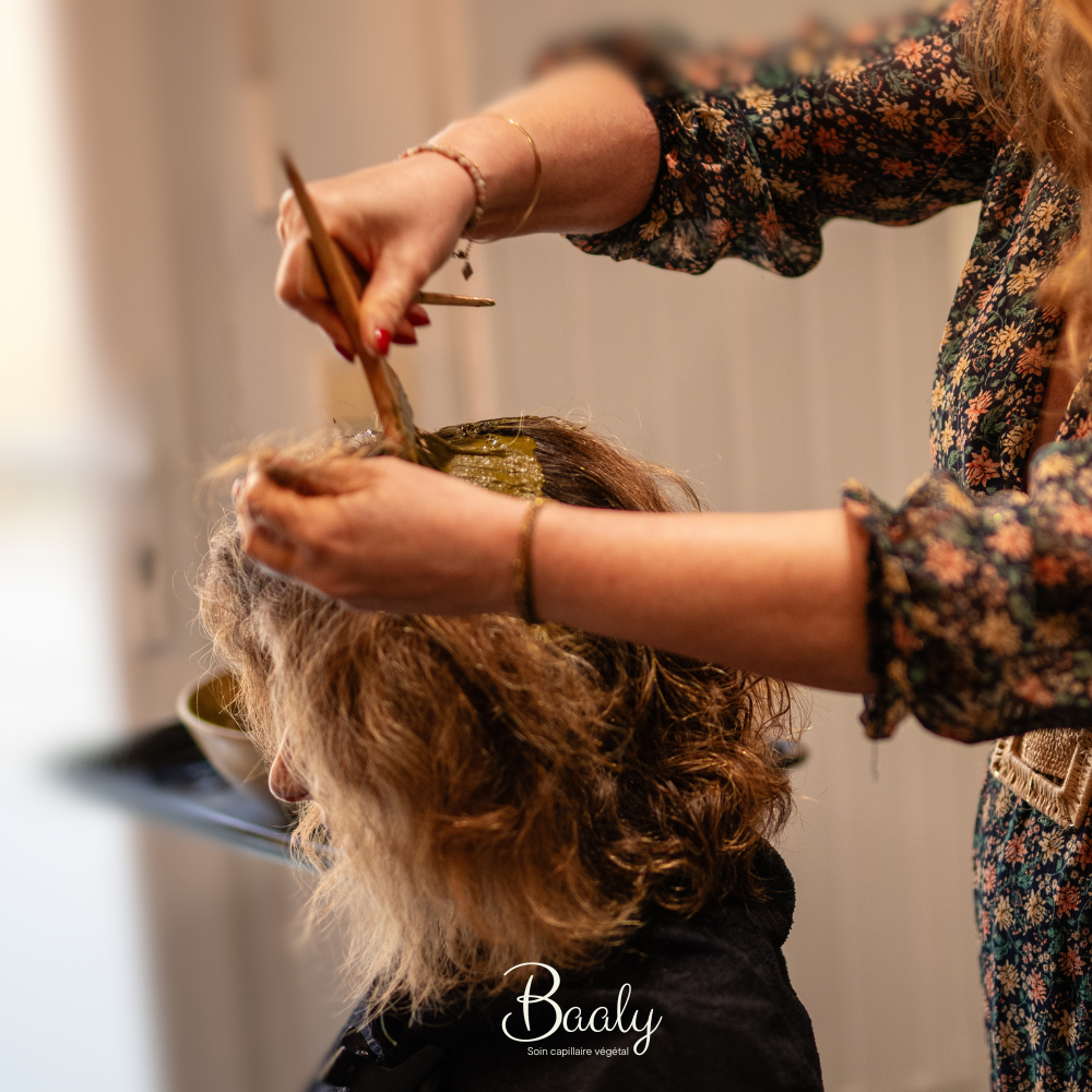 Application de coloration végétale en salon par une experte. Utilisation de poudres de plantes naturelles pour un résultat capillaire personnalisé, respectueux du cheveu et du cuir chevelu.